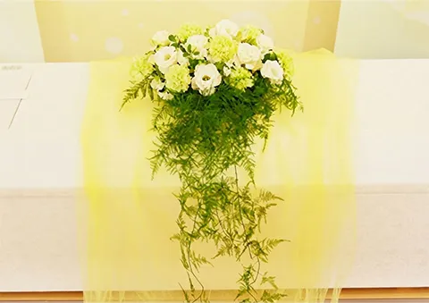 白い棺の上に置かれた、白と緑の花の花束